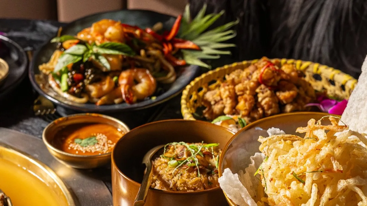 A tabletop mookata grill with meats searing on the dome and vegetables simmering in the broth moat.