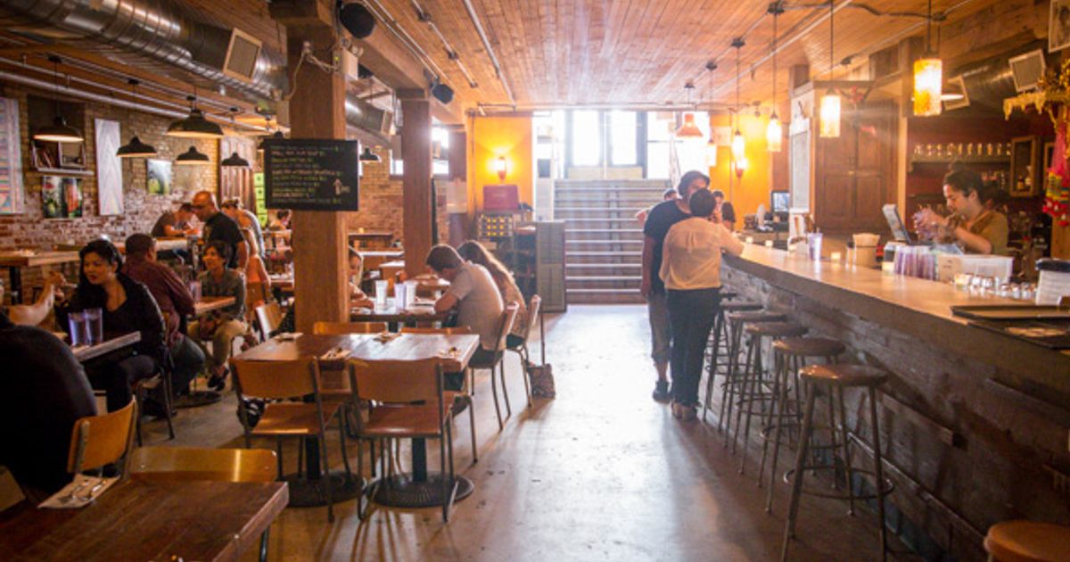 The vibrant, bustling interior of Pai Northern Thai Kitchen with warm lighting and Thai-inspired decor.
