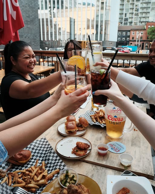Patio table at The Main Exchange: fries in checkered baskets, sliders, and a Coors Light pitcher — from venue Instagram @mainxking