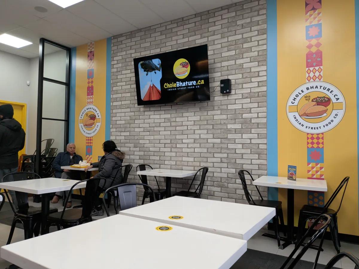 The clean, modern dining area with yellow accents and exposed brick