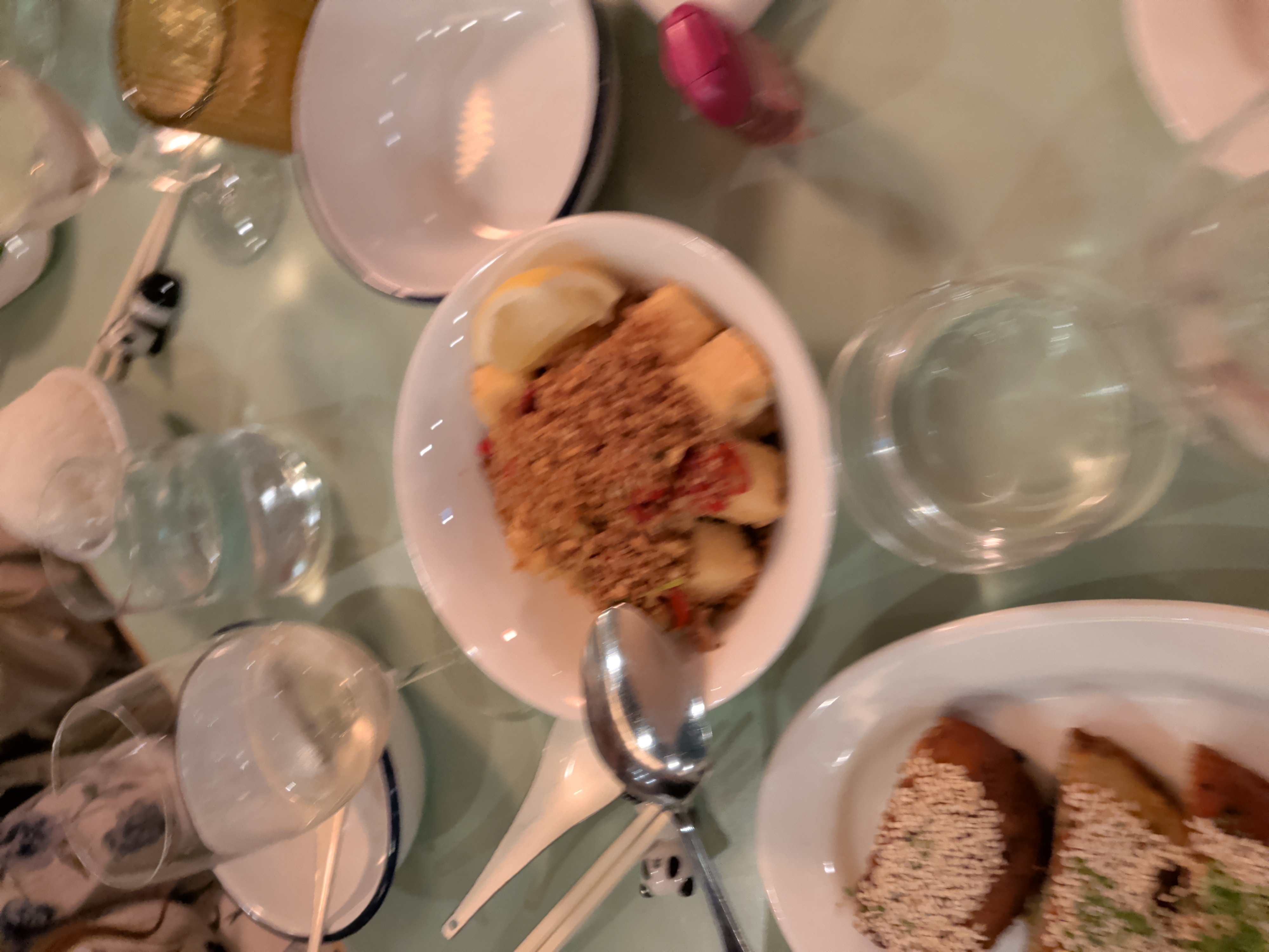 A comforting bowl topped with spiced breadcrumbs and lemon alongside wine glasses