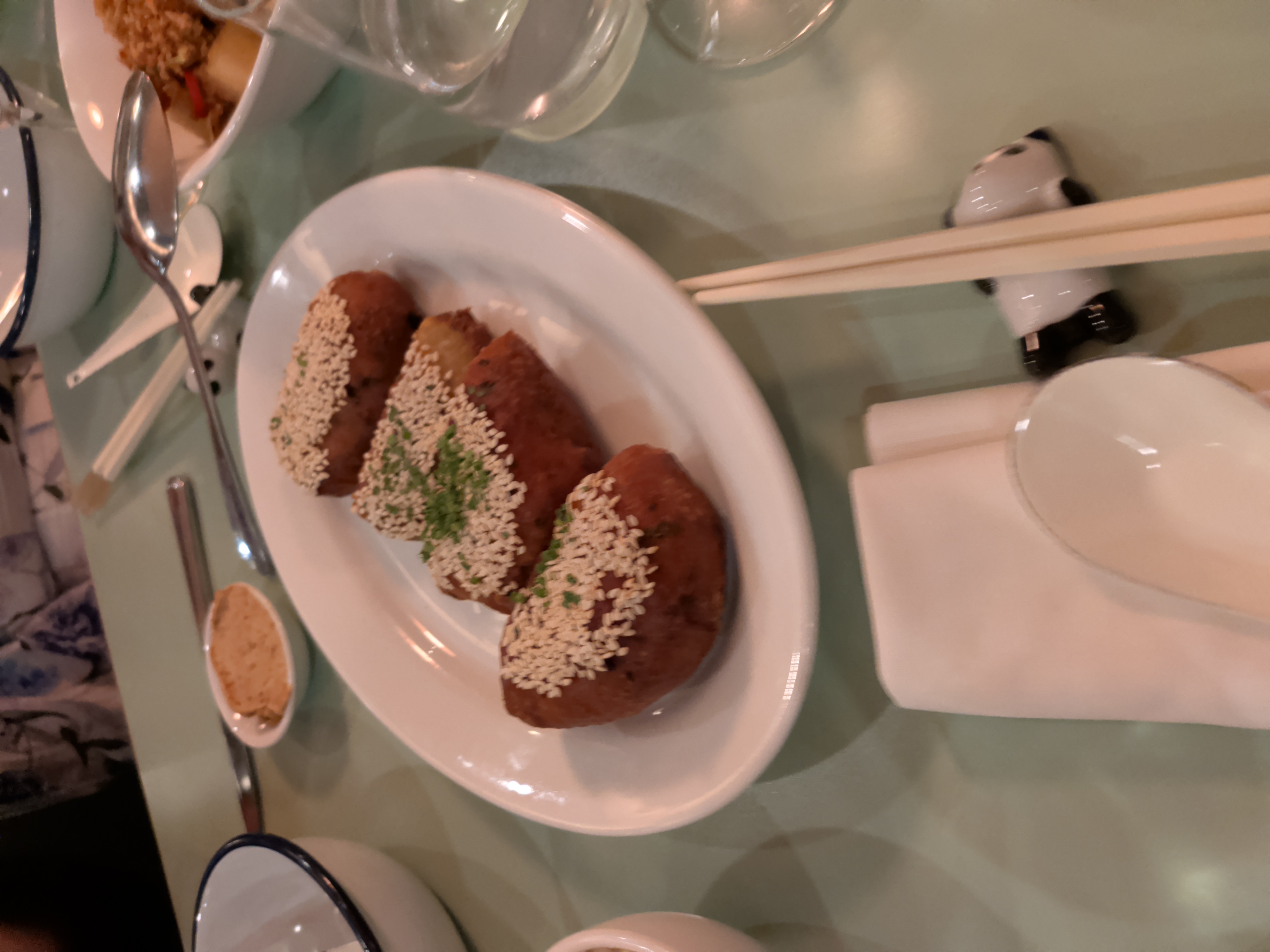 Sesame-crusted golden dishes served on a white plate with chopsticks and a panda rest