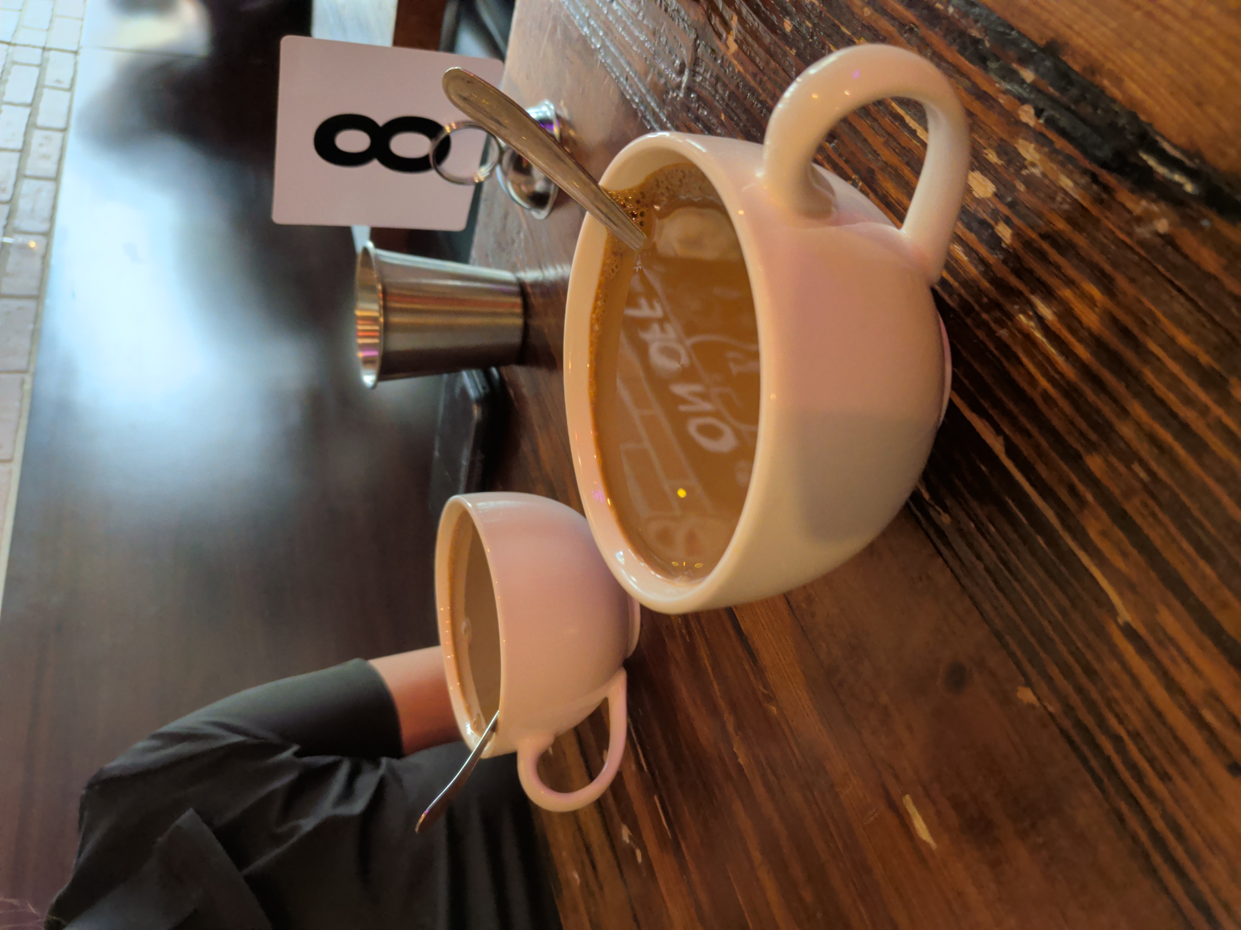 Two white ceramic mugs filled with hot Kopi on a rustic wooden table.