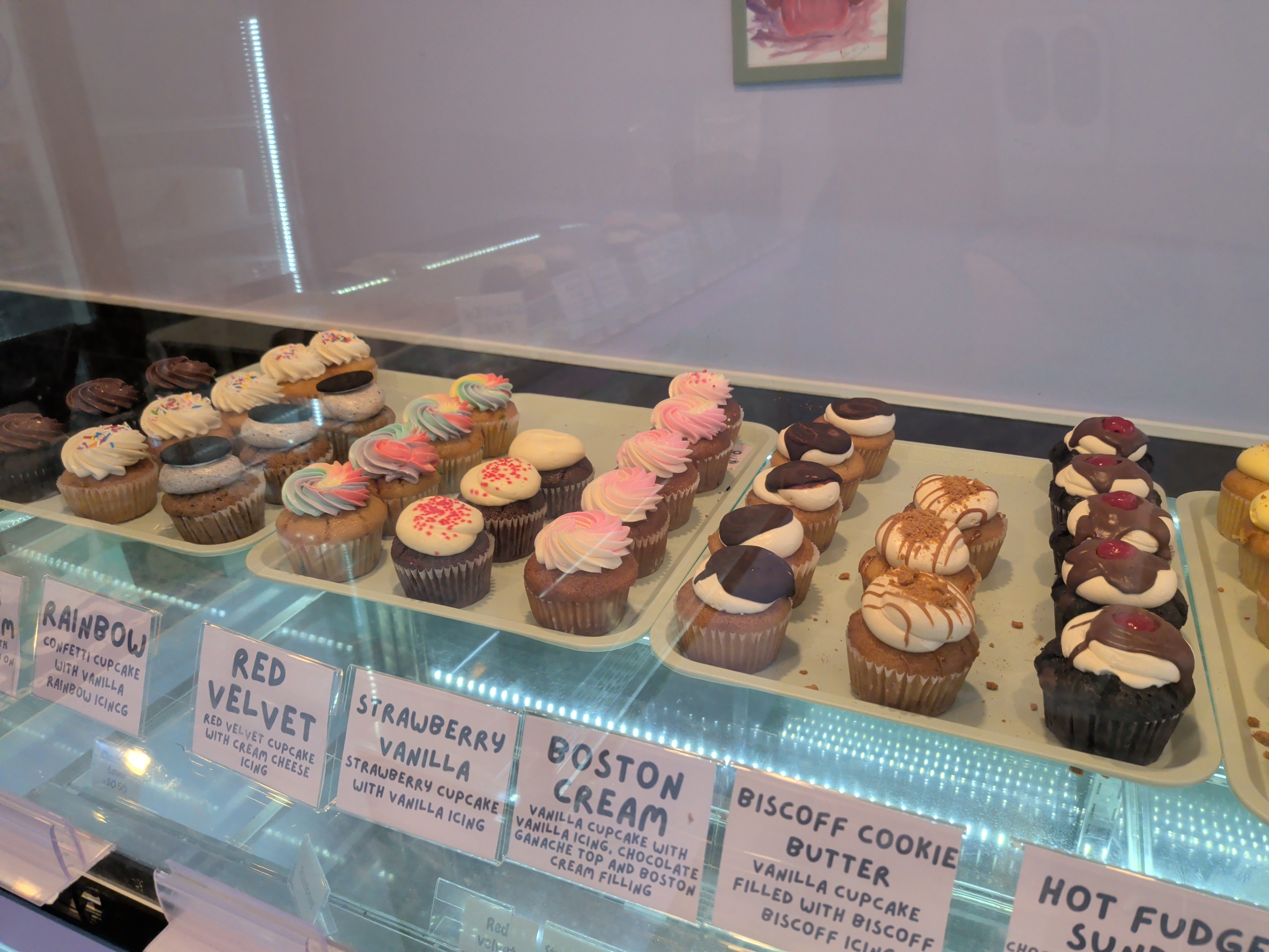 Close-up view of various cupcakes inside the glass display case