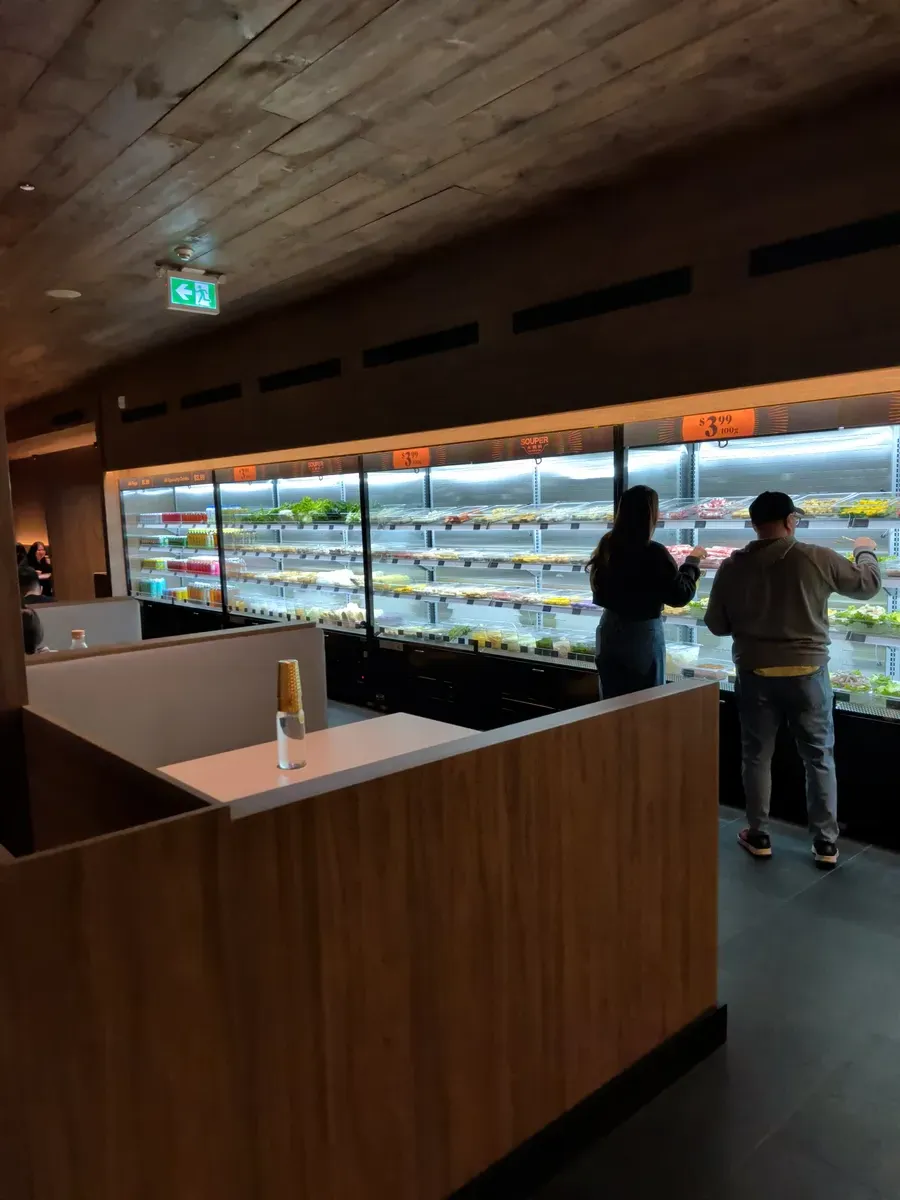 Customers selecting ingredients from the refrigerated display cases