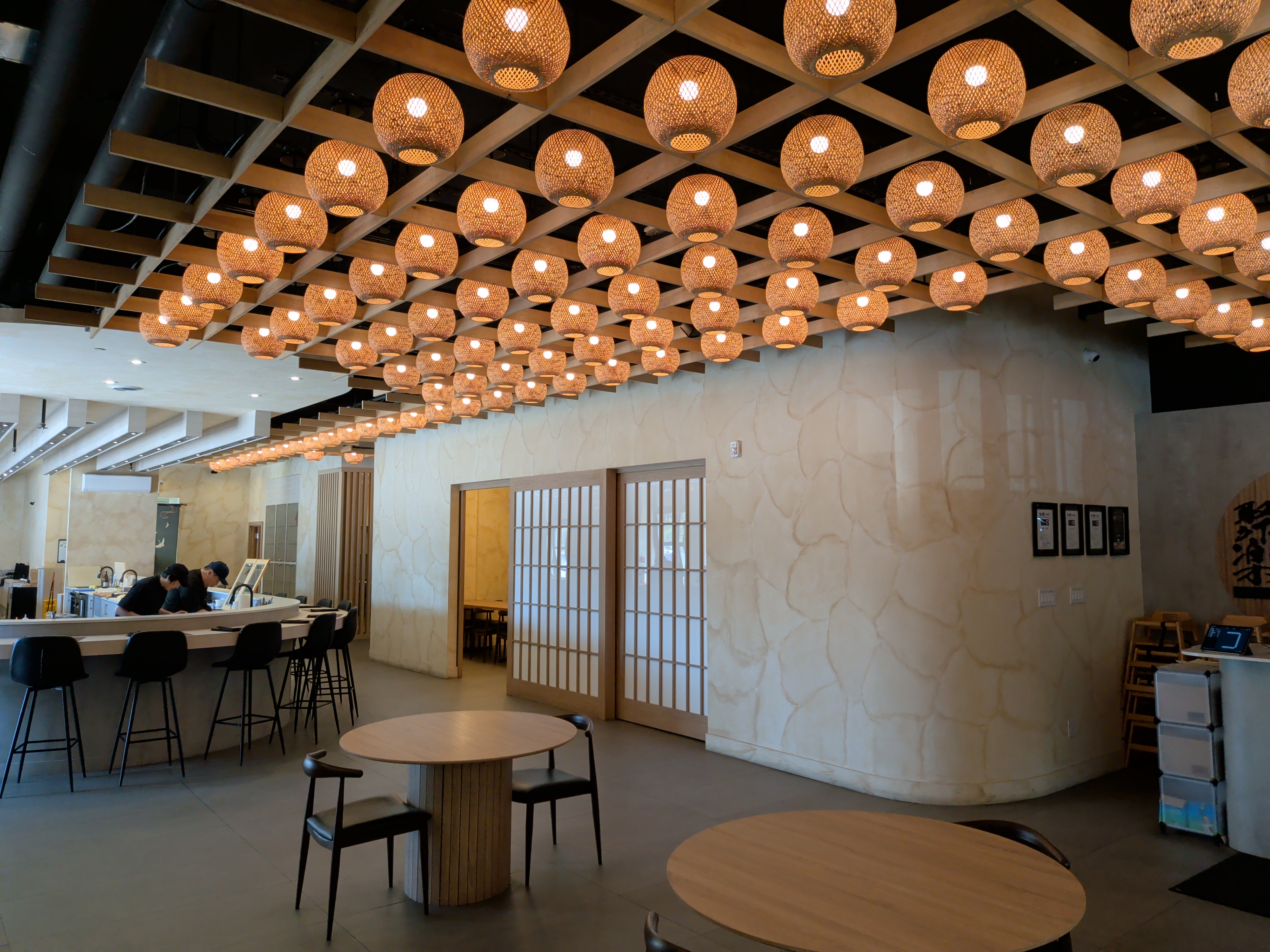 A wide view of the bright, modern dining room with woven pendant lights