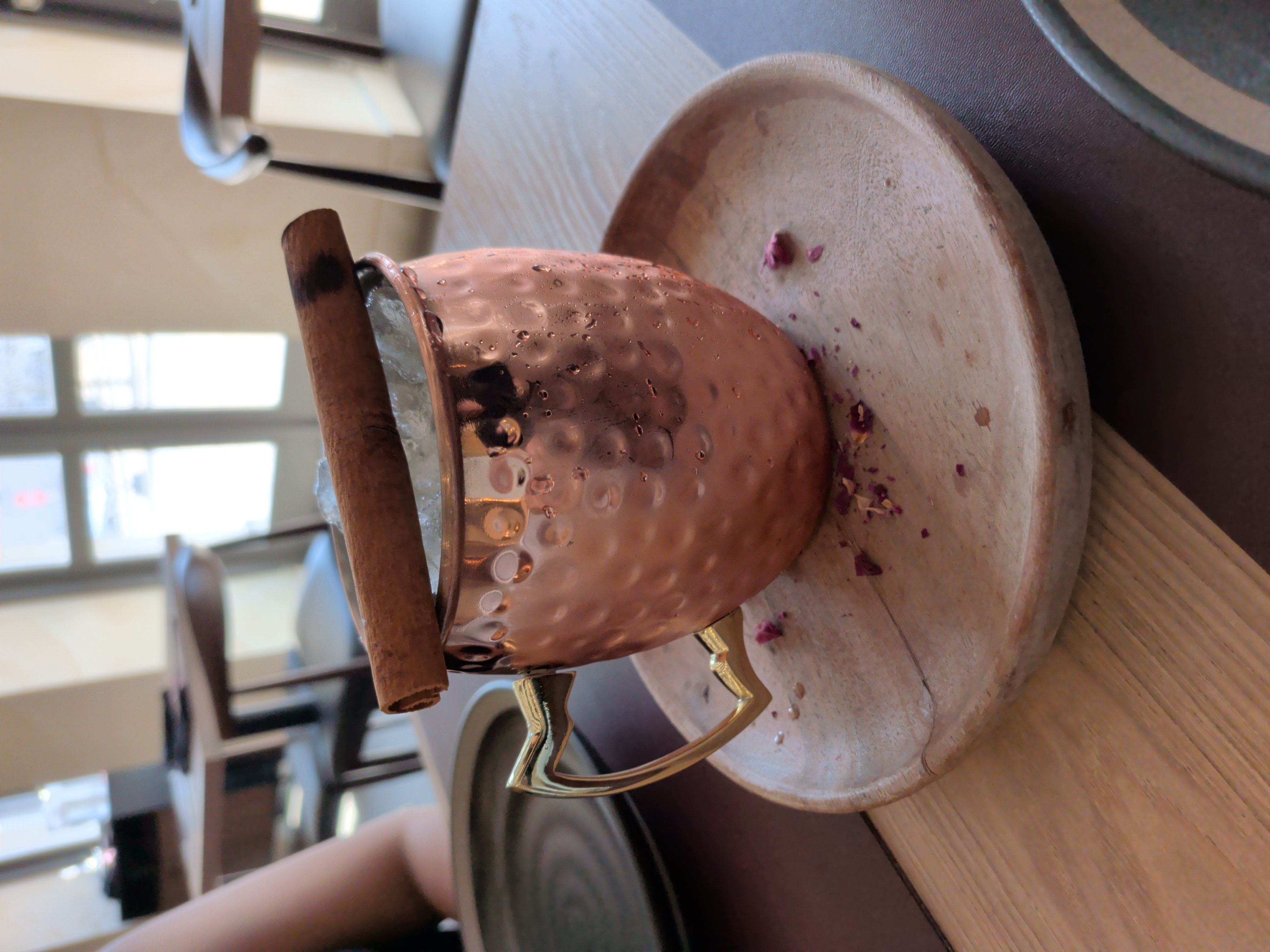 A cocktail in a copper mug garnished with a cinnamon stick