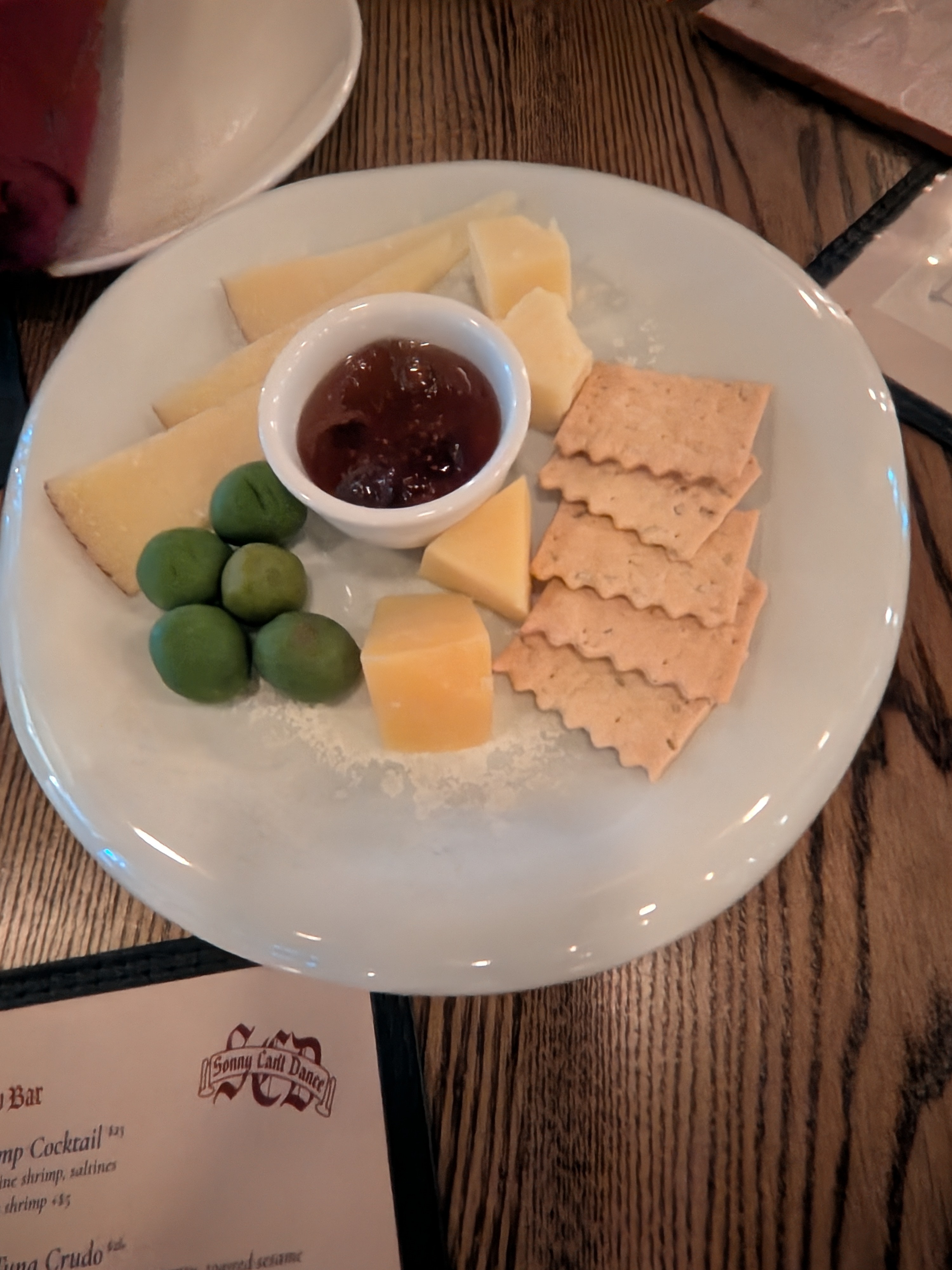 Complimentary cheese plate with olives, jam, crackers, and two cheeses