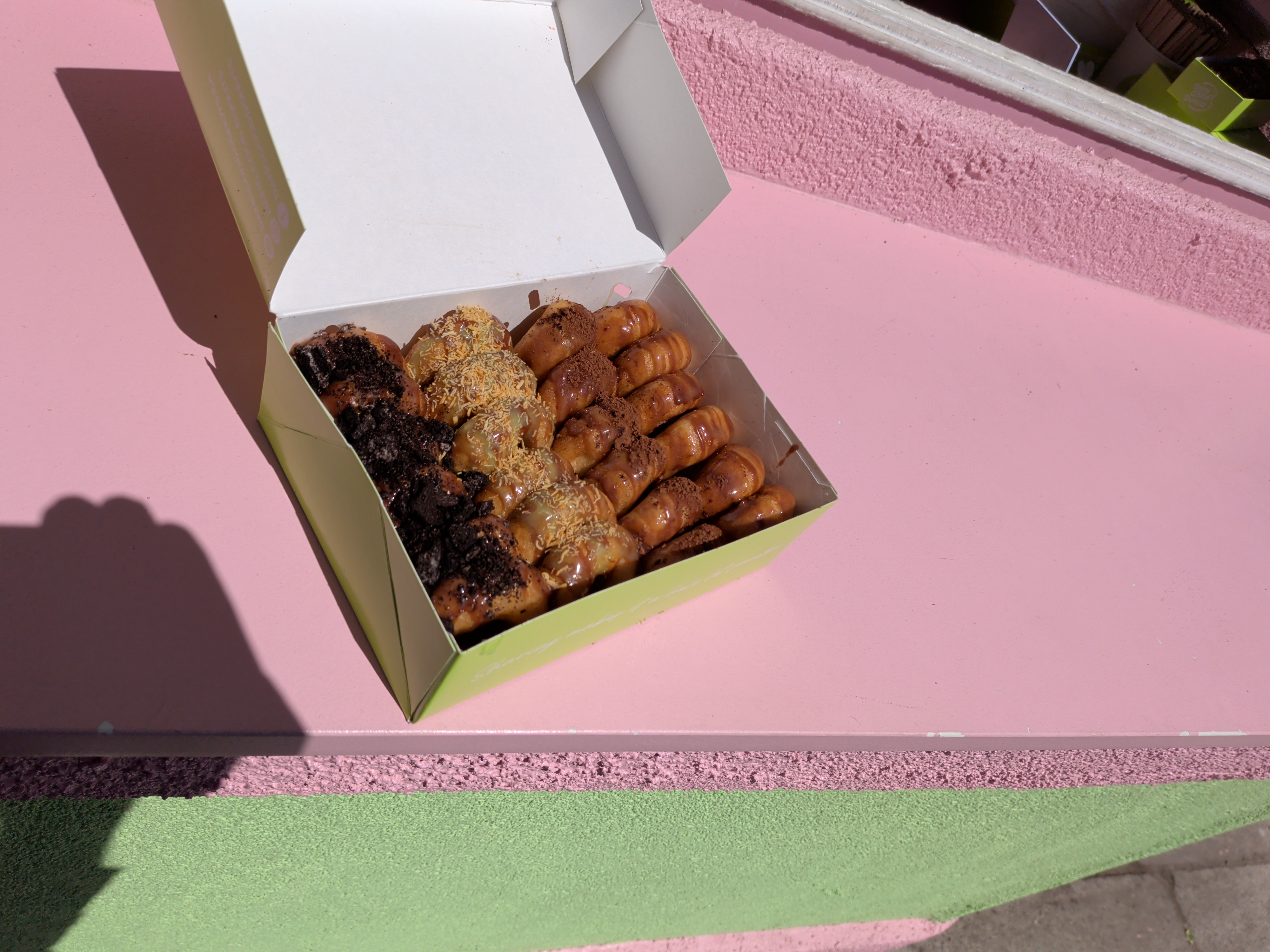 A 24-pack box of assorted mini donuts featuring various toppings