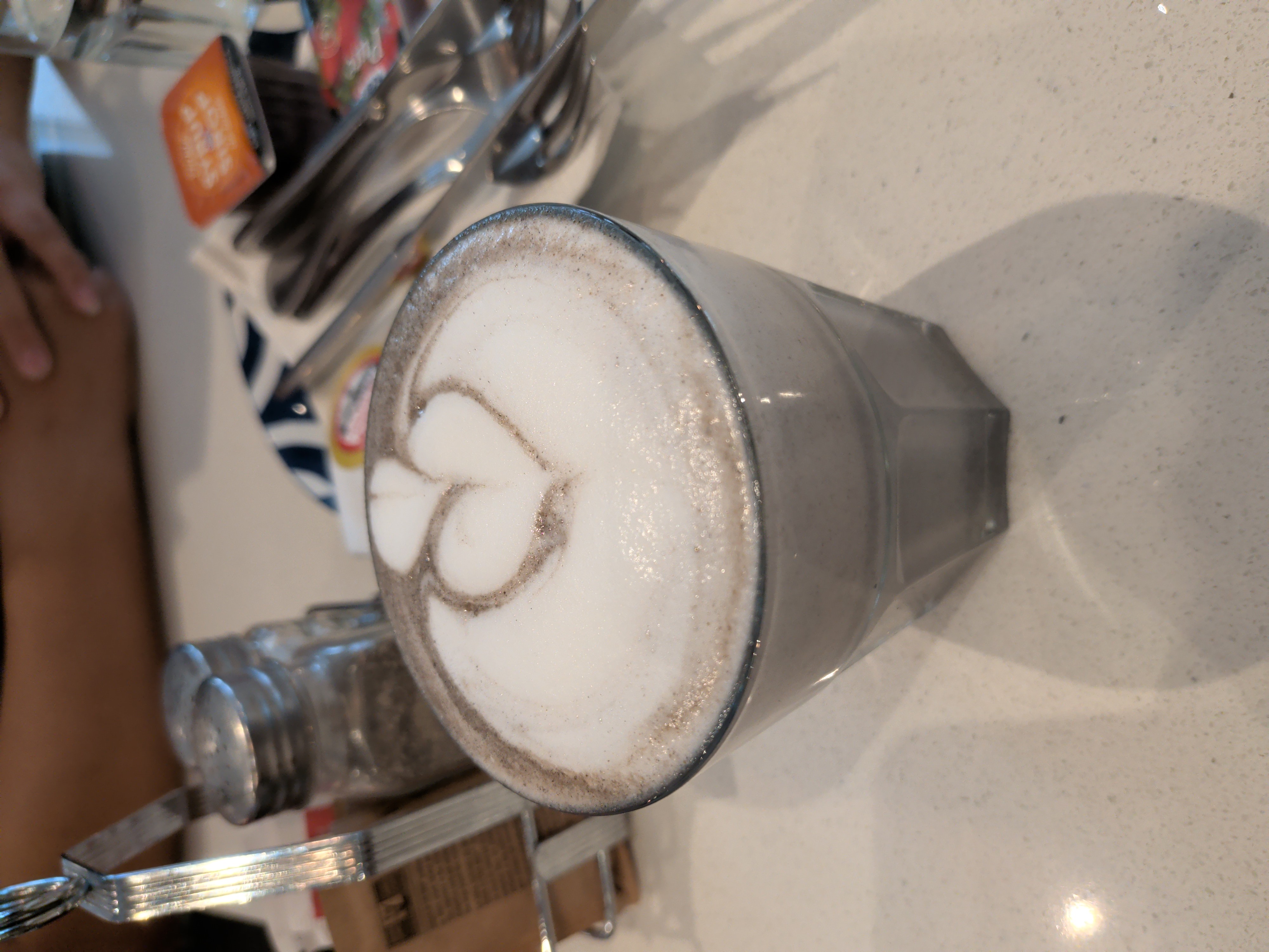 Hot black sesame latte in a clear glass with latte art