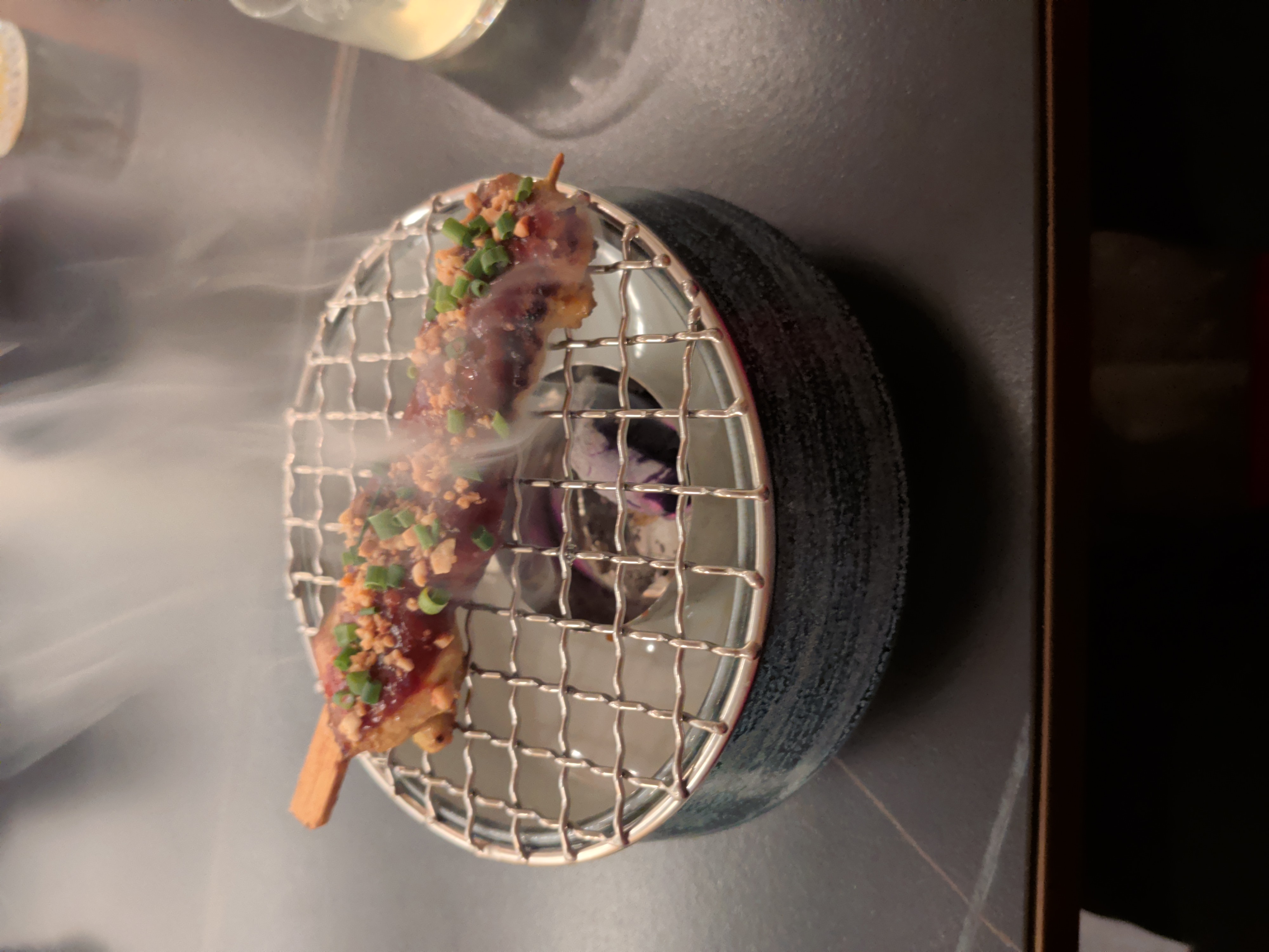 Chicken skewer served over a smoking piece of coal