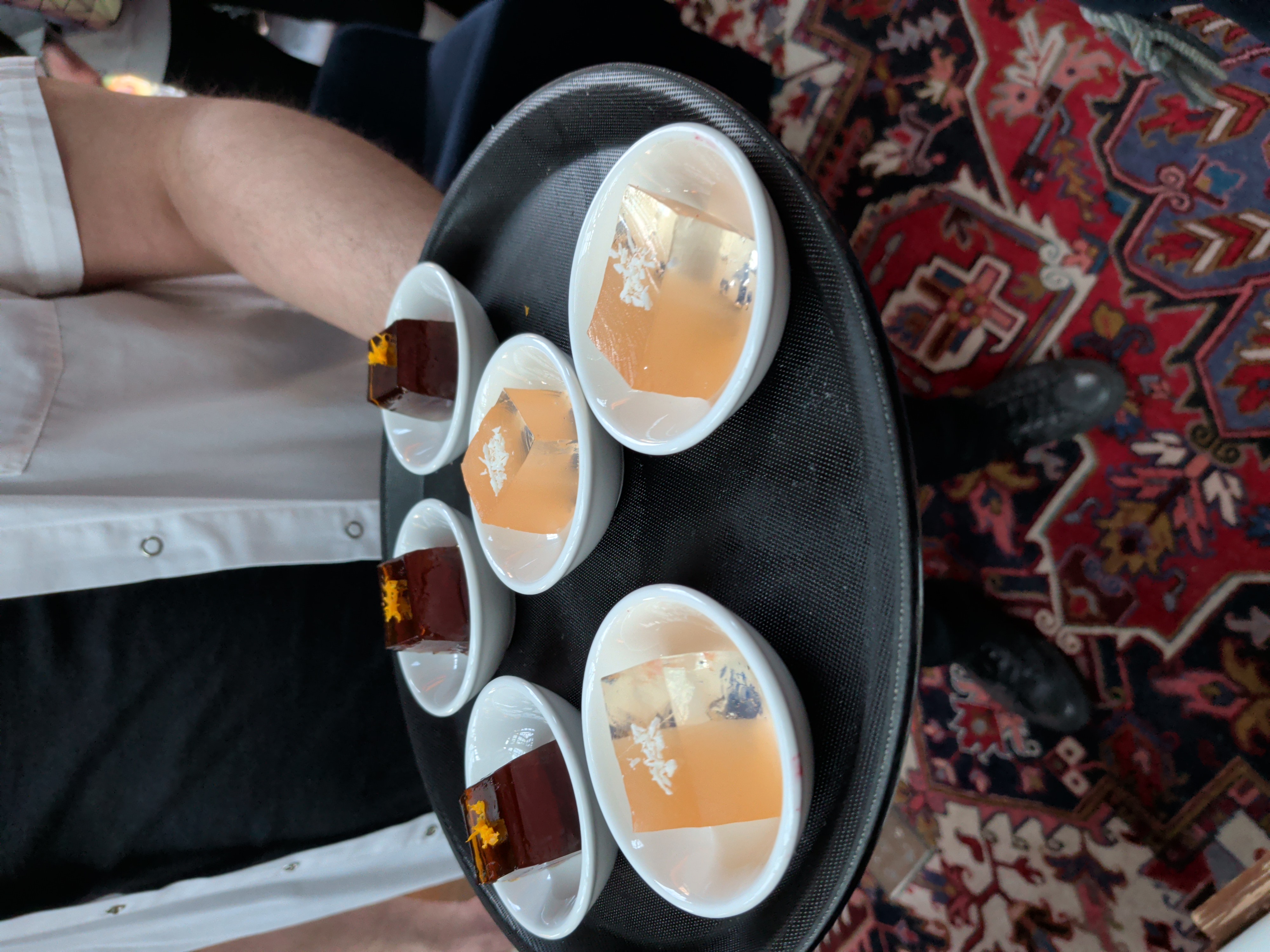 A tray of colorful, elegant jello shots being served.