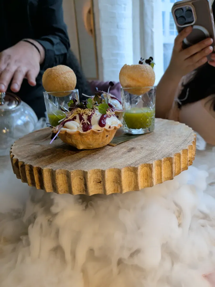 Pani puri served on a wooden pedestal with dry ice